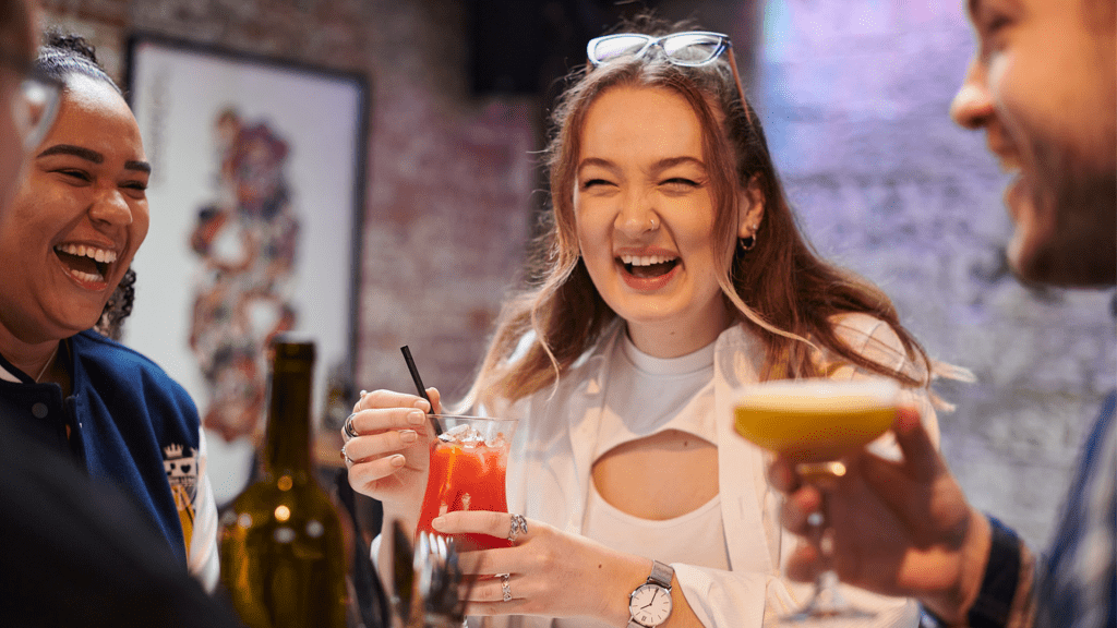 Students laughing and enjoying drinks at a bar in Ormskirk.