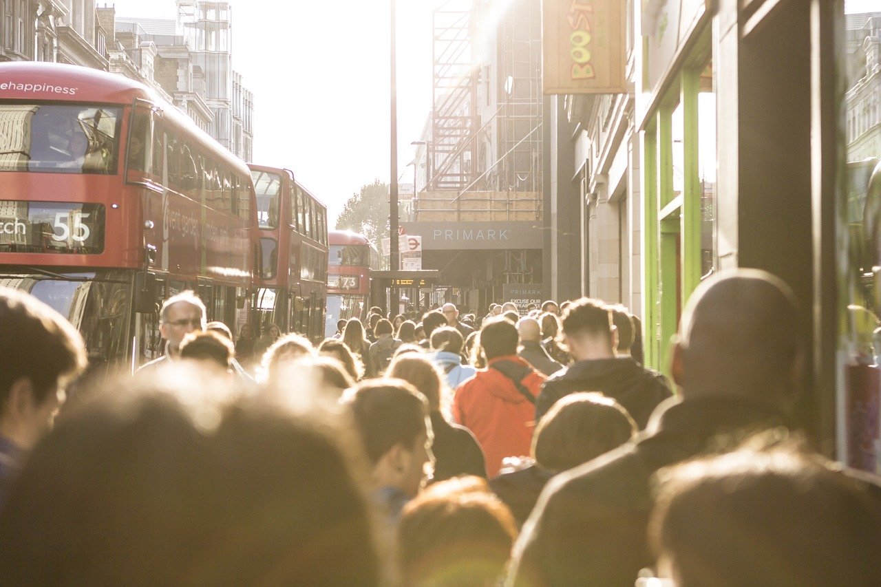 Crowds walking through London. A bus can be seen in the left of the image, and a Primark is shown in the background.