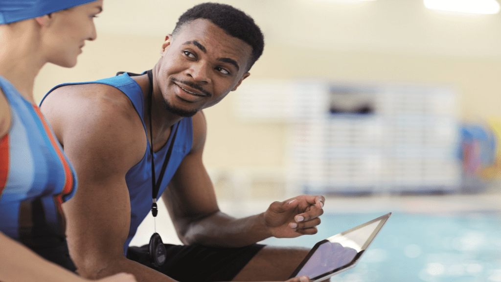 swimmer and coach sat at the side of a swimming pool