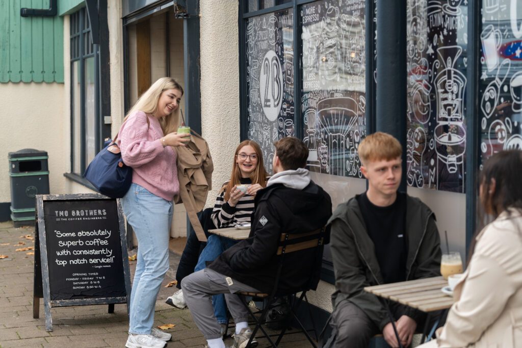 Students socialising outside coffee shop in town centre