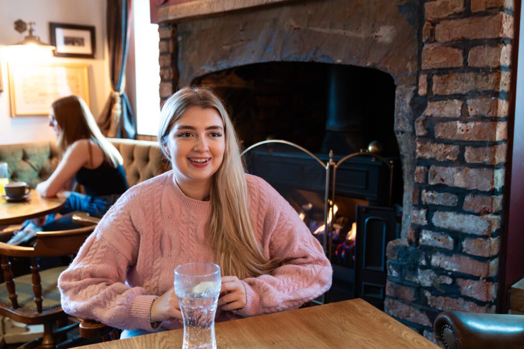 Student sitting by fireplace in local pub