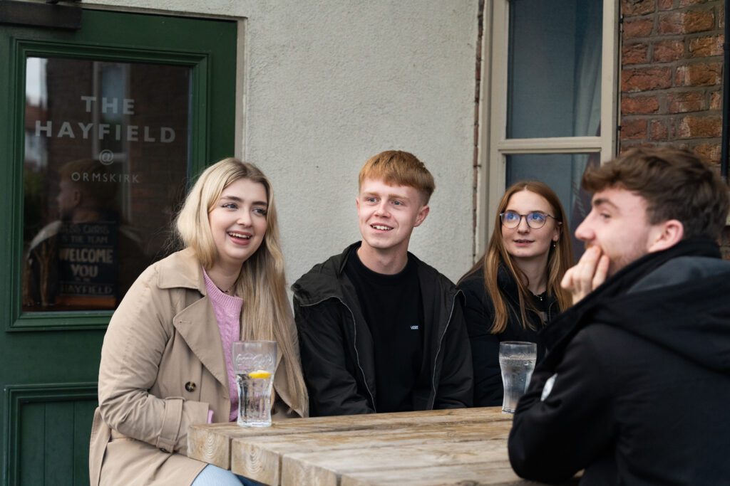 Students sitting and drinking in beer garden outside local pub